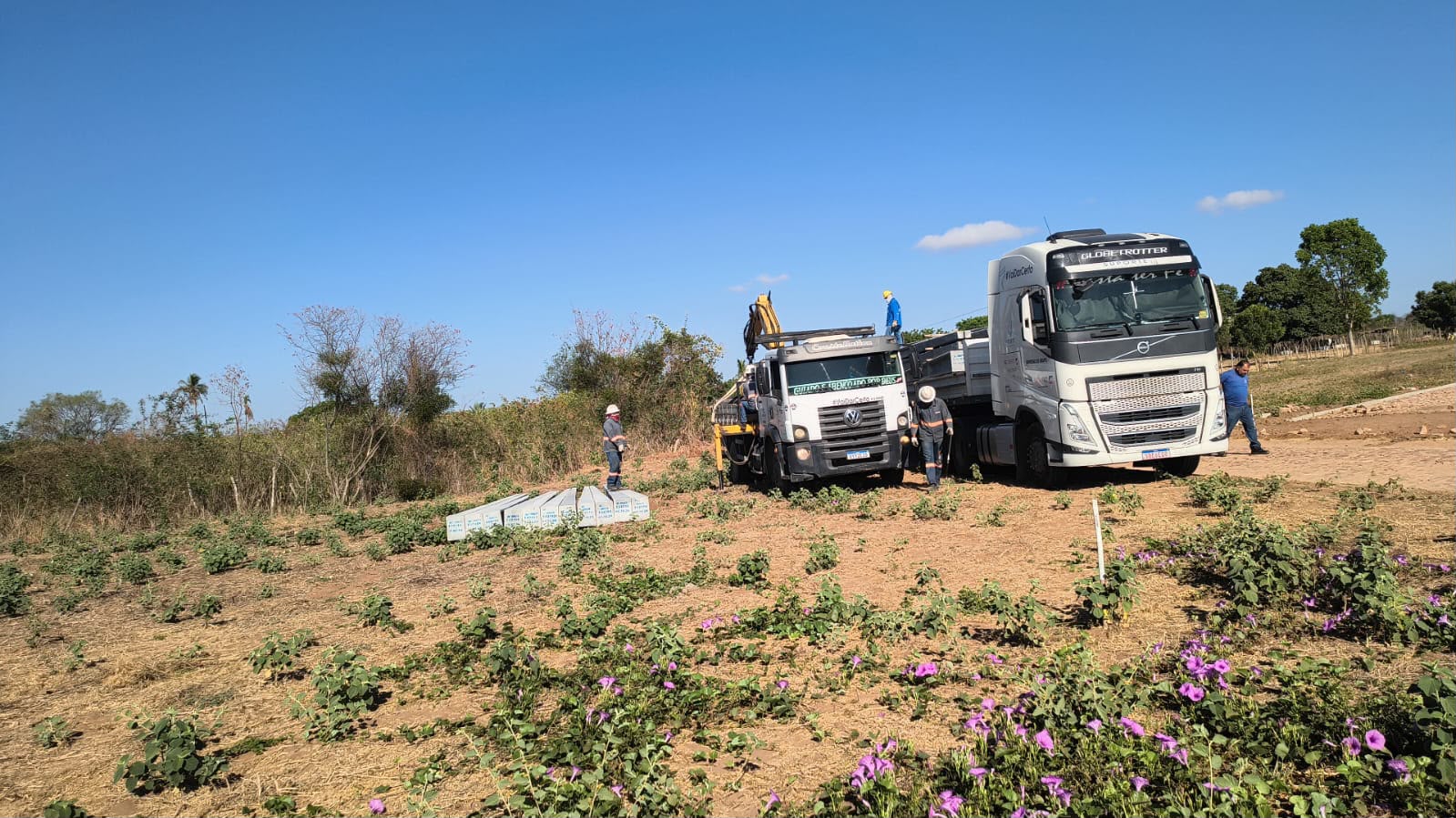 Caminhões e equipe junto a materiais para implantação no terreno
